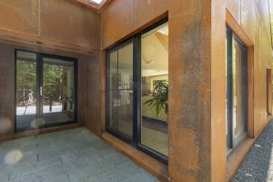 Metal exterior walls featuring a natural patina with a reddish-brown hue.