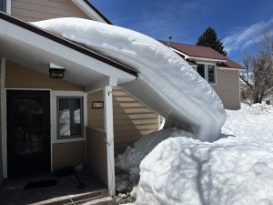 Snow forming an arch sliding off a rooftop