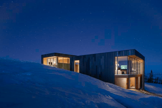 Nighttime exterior view of rectangular residence.